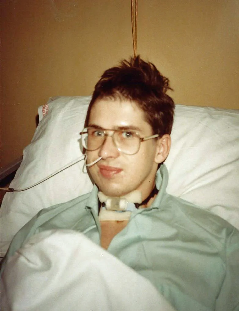 John Murphy in a hospital bed with a tracheostomy tube in his neck and a feeding tube in his nose