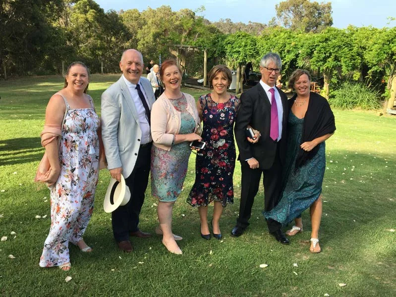 A group of seven adults in smart clothes standing on a lawn