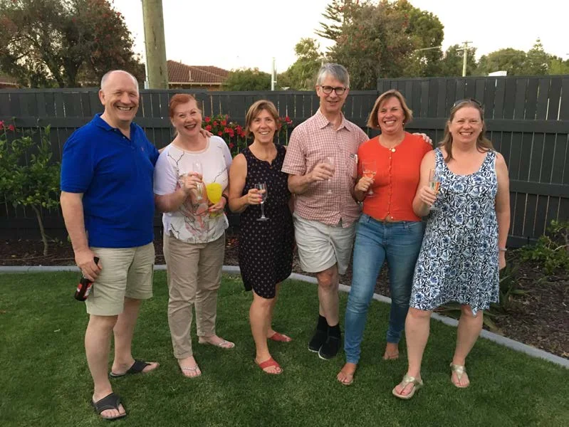 A group of adults standing in a garden holding drinks